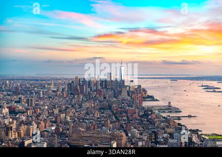 Una spettacolare vista panoramica sopraelevata dello skyline di Downtown Manhattan e dei quartieri circostanti sotto un vibrante cielo al tramonto. Foto Stock