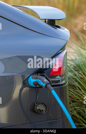 Primo piano di ricarica di veicoli elettrici/EV presso la stazione di ricarica pubblica/punto di carico per auto elettriche con cavo, connettore e ingresso del veicolo Foto Stock