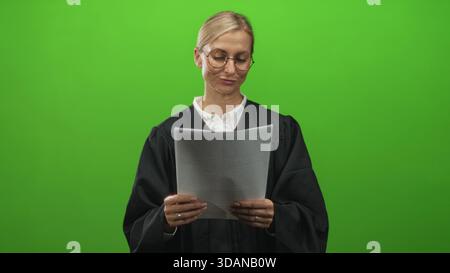 Giudice donna che legge la carta, tiene il documento con entrambe le mani in uno studio con schermo verde; calma fiducia. Foto Stock