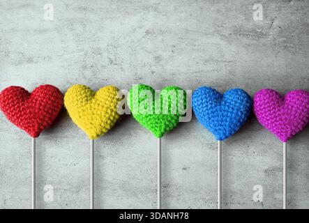 San Valentino. Cuori a maglia multicolore su uno sfondo grigio. Posizione piatta Foto Stock