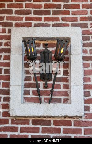 Antica torcia in ferro battuto su una parete in mattoni rossi rustici Foto Stock