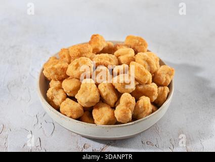 Pop corn di pollo croccante in un recipiente di ceramica su sfondo bianco. Snack o antipasto fast food. Primo piano Foto Stock