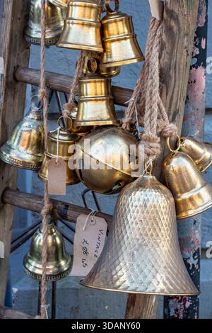Primo piano astratto di ottone decorativo e campane e baule natalizie dorate appese all'esterno di un negozio di decorazione d'interni a Winchester, Hampshire, Foto Stock