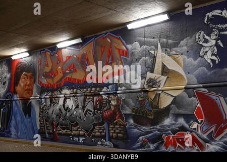 Luci fluorescenti sul soffitto di un tunnel di cemento sopra graffiti e opere murali sul sottopassaggio a Dijksgracht, Amsterdam, Paesi Bassi, di notte. Foto Stock