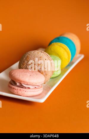 macaron rotondi di diversi colori su un piatto rettangolare oblungo bianco Foto Stock