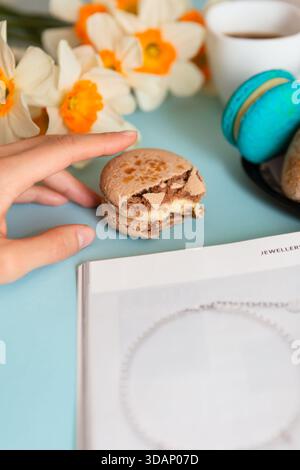 Deliziosa colazione dolce con macaron e caffè su sfondo blu Foto Stock