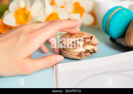 Deliziosa colazione dolce con macaron e caffè su sfondo blu Foto Stock