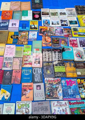 IPOH, MALESIA - 09 NOVEMBRE 2025: Una foto in alto di un'esposizione con una pila di libri e riviste malesi vintage in vendita. Foto Stock