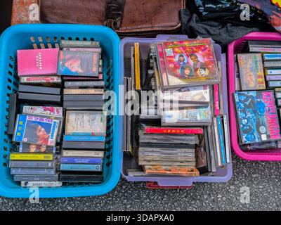 IPOH, MALESIA - 09 NOVEMBRE 2025: Una vista dall'alto di vari nastri e compact disc vintage impilati esposti in cesti di plastica colorati Foto Stock