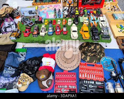 IPOH, MALESIA - 9 NOVEMBRE 2025: Vista dall'alto di una bancarella del mercato delle pulci che espone vecchi libri, giocattoli, cappelli e utensili meccanici. Foto Stock