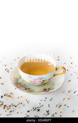 Tè in piattino, sfondo bianco con foglie di tè in primo piano, copia dello spazio sopra Foto Stock