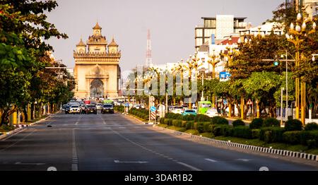 Un ampio viale che conduce ad un grande arco ornato in un ambiente urbano. Foto Stock