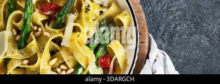 Fituccine con pesto di basilico e pinoli su un piatto bianco. Fituccine al pesto secondo una tradizionale ricetta italiana su un backgroun scuro Foto Stock