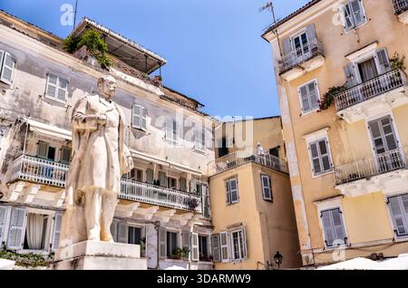 Statua in una piccola piazza circondata da edifici di epoca veneziana nella città vecchia di Corfù, Corfù, Grecia, che mette in risalto il carattere urbano storico. Foto Stock