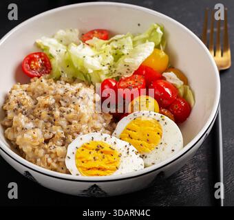 Colazione salutare. Ciotola di farinata d'avena, verdure fresche e uova sode. Foto Stock