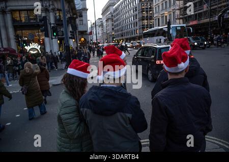 I lavoratori di Londra si recano con i cappelli di Babbo Natale durante la festa di Natale in compagnia a Piccadilly, nel centro di mayfair, Londra, Regno Unito Foto Stock