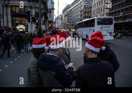 I lavoratori di Londra si recano con i cappelli di Babbo Natale durante la festa di Natale in compagnia a Piccadilly, nel centro di mayfair, Londra, Regno Unito Foto Stock