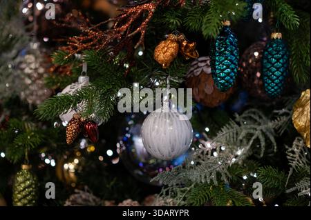 Baule natalizie in oro e argento appese su rami decorati di alberi con luci accese, che creano un'atmosfera festiva luminosa e classica Foto Stock