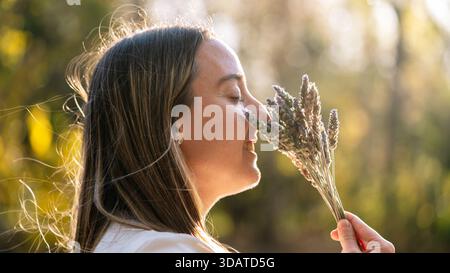 Donna sorridente che si gode il profumo dei fiori di lavanda Foto Stock