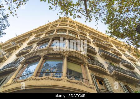 La vista della facciata ornata di Casa Batlló si estende verso il cielo, con i suoi intricati balconi che gettano ombre sulla pietra illuminata dal sole, un capolavoro di architettura Foto Stock