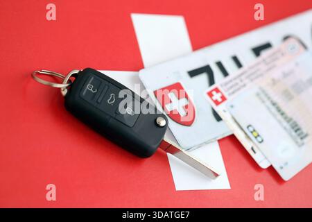 Targa Svizzera e chiave di accensione sulla bandiera svizzera primo piano. Patente di guida e concetto di immatricolazione Foto Stock