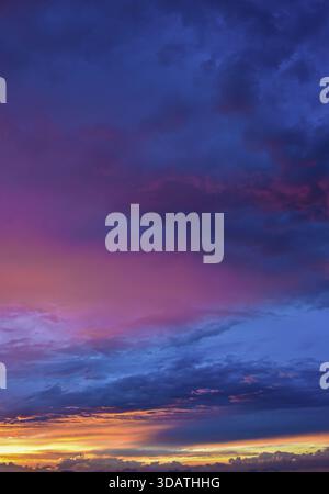 Bellissimo e tranquillo momento del crepuscolo nel tardo pomeriggio. Nuvole delicate e vellutate immerse in calde e intense tonalità dorate e rosse su un ampio orizzonte aperto. Foto Stock