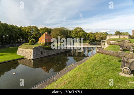 Vista di un castello medievale di Kalmar con mura in pietra e un edificio dal tetto rosso riflesso nell'acqua tranquilla del fossato sotto un cielo luminoso, Kalmar e Kalmar Foto Stock