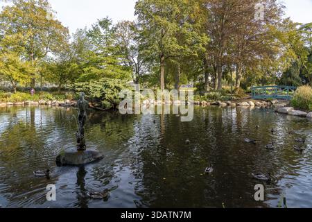 Vista di un tranquillo laghetto che riflette gli alberi con anatre che nuotano intorno a una statua in acqua, Kalmar, Kalmar County, Svezia. Foto Stock