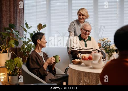 Uomo caucasico anziano sorridente mentre si siede con una donna anziana nella casa di riposo Foto Stock