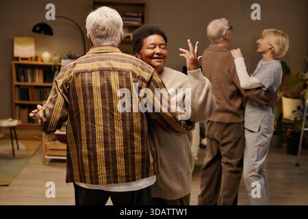 Donna nera anziana e uomo caucasico anziano che ballano gioiosamente nella casa di riposo Foto Stock