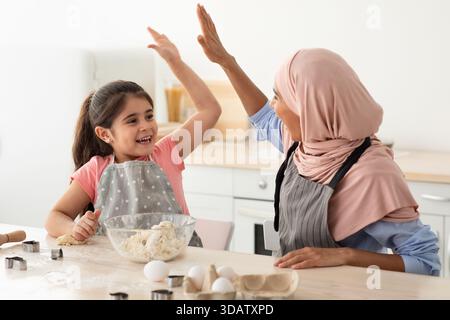 Madre e figlia si godono una gioiosa sessione di cottura insieme in cucina Foto Stock