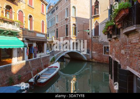 Edifici tradizionali con riflessi lungo lo stretto canale di Venezia in Italia in una giornata di sole Foto Stock