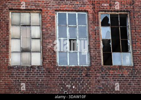 Tre vecchie finestre rotte su un grintoso muro di mattoni Foto Stock