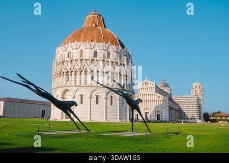 Pisa, Italia - 26 giugno 2025: Il Battistero domina il primo piano, con la sua struttura circolare in marmo e la cupola in terracotta, mentre il Duomo e. Foto Stock