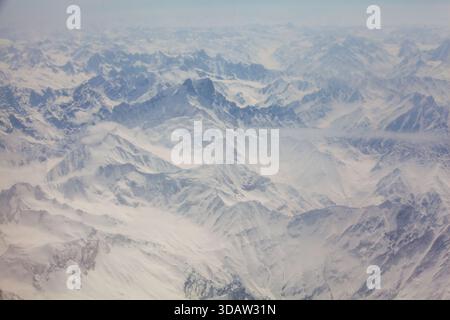 La vista aerea delle vette innevate e delle valli crea uno splendido arazzo bianco e grigio, che mette in risalto la bellezza aspra del terreno montuoso, Foto Stock
