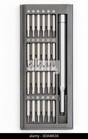 Colpo d'asta di un kit di plastica nera contenente varie misure e tipi di punte per cacciaviti in metallo argento e un manico. Il kit è organizzato con un'etichetta Foto Stock