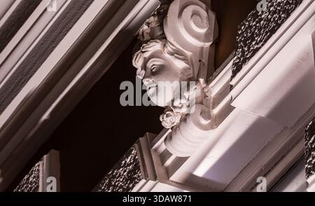 Primo piano di una classica facciata scolpita su una facciata di un edificio storico a Tbilisi, Georgia. Splendidi dettagli ornamentali in una luce soffusa da sera, che si riflette Foto Stock