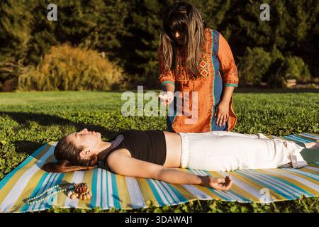 Due donne si impegnano in una tranquilla sessione di bagno all'aperto in nuova Zelanda durante l'autunno, circondate dalla natura. Una donna ha un diapason, creat Foto Stock
