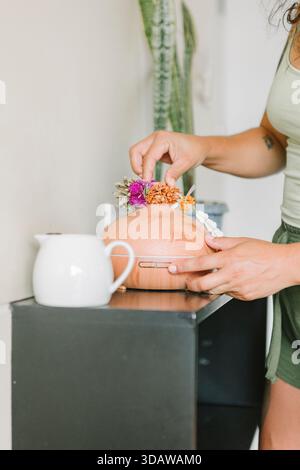 Una donna regola un purificatore d'aria posizionato su un tavolo, circondato da un arredamento naturale. La scena riflette un'atmosfera serena incentrata sulla salute e il benessere Foto Stock