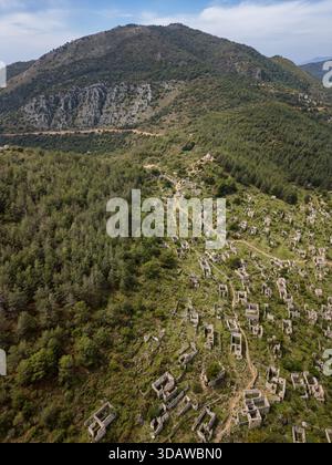 Vista aerea della città greca ortodossa cristiana abbandonata di Kayakoy in Turchia. Rovine e vecchie strutture in pietra sono annidate in una lussureggiante lan montuosa Foto Stock