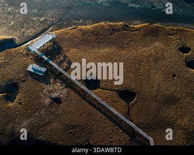 Veduta aerea di un molo intempestivo che si estende attraverso la palude dorata, gettando lunghe ombre sotto il sole del pomeriggio, Gloucester, Massachusetts, United Foto Stock