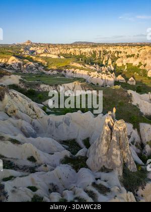 Vista aerea della Valle dell'amore in Cappadocia, Turchia, con formazioni rocciose uniche e paesaggi verdeggianti sotto un cielo azzurro. Il panorama è spettacolare Foto Stock