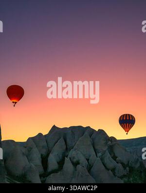 Splendida vista delle mongolfiere che si innalzano sul paesaggio roccioso della Cappadocia, Turchia, all'alba. I colori vivaci illuminano il cielo, creando Foto Stock