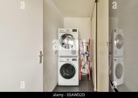 Un'elegante e moderna area lavanderia con lavatrici e asciugatrici impilate e soluzioni di stoccaggio che mostrano funzionalità e design in un compac Foto Stock
