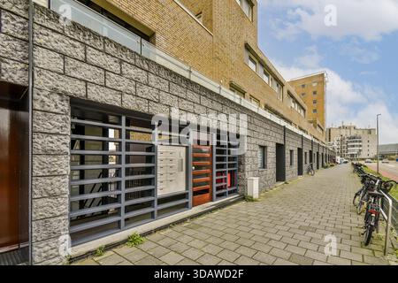 Una vista dell'esterno di un edificio contemporaneo, che mostra elementi di design architettonico e un marciapiede lastricato. L'ambiente include biciclette nelle vicinanze e. Foto Stock
