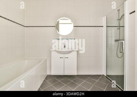 Un bagno contemporaneo con finiture eleganti, linee pulite e un design minimalista. La disposizione include doccia, vasca da bagno e un elegante specchio Foto Stock