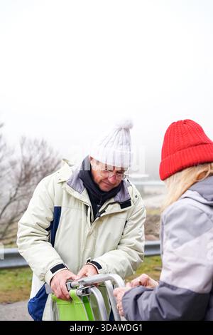 Una coppia più anziana si è impegnata in attività invernali, godendosi il freddo all'aperto. Sono vestiti con calore con cappotti e cappelli a maglia, che incarnano gioia e. Foto Stock