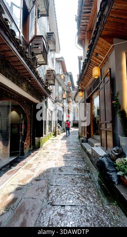 Affascinante strada stretta nella città vecchia di Fenghuang, in Cina, che presenta un'architettura tradizionale splendidamente conservata, facciate in legno e lanterne sospese Foto Stock