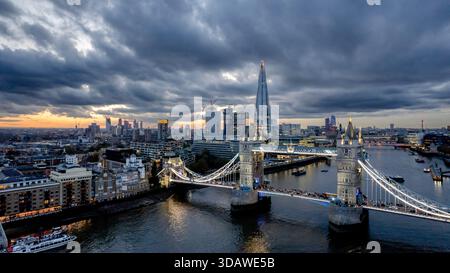 Una splendida vista aerea del Tower Bridge durante il tramonto con l'iconico skyline che presenta lo Shard e il vibrante paesaggio urbano di Londra, evidenziando il suo arco Foto Stock