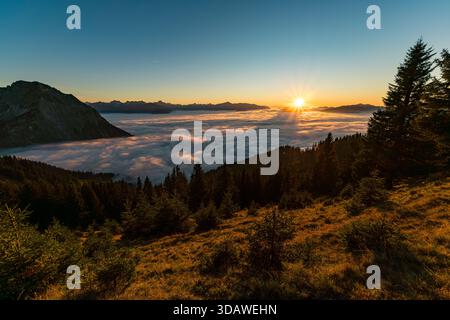 Cattura un'alba serena e autunnale su un mare di nuvole dalla cima dei picchi Sonnenkopf con magnifiche vedute delle Alpi Allgaeu Foto Stock